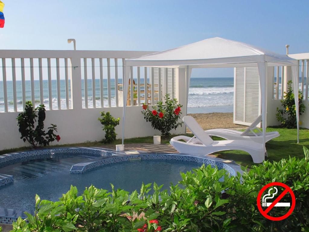 a swimming pool with a gazebo and chairs next to the beach at Los Sonidos de las Olas in Santa Marianita