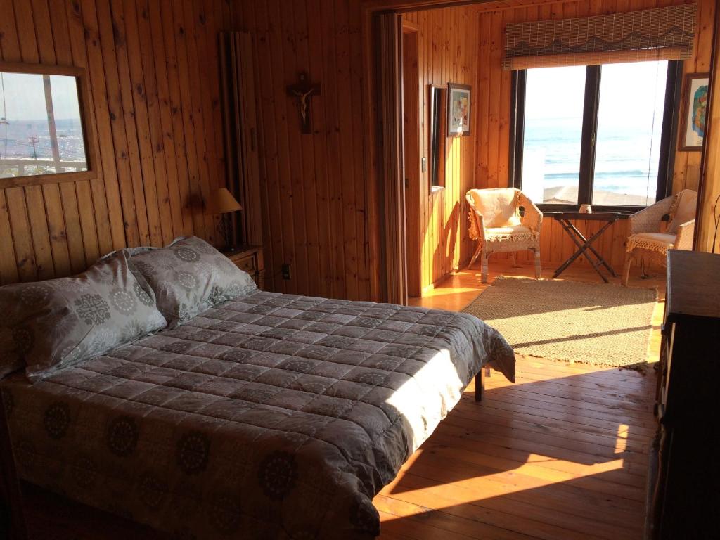 a bedroom with a bed in a room with windows at Casa en maitencillo in Maitencillo