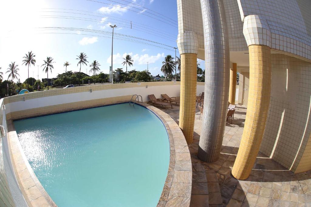 uma piscina ao lado de um edifício com palmeiras em Real Praia Hotel em Aracaju