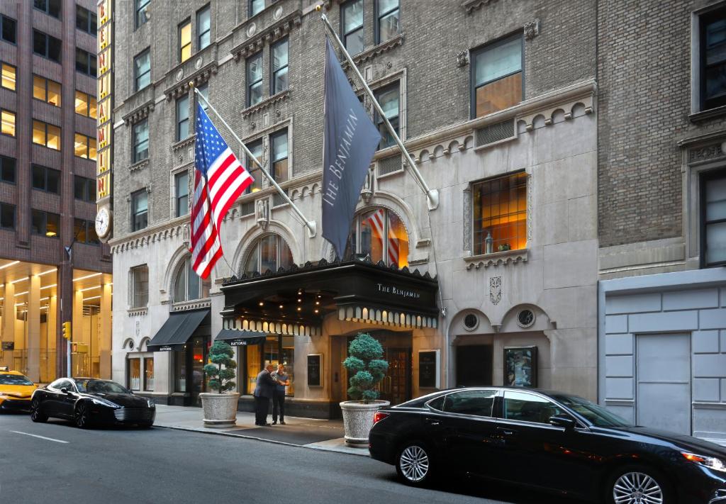 un coche negro estacionado frente a un edificio con banderas en The Benjamin Royal Sonesta New York en Nueva York