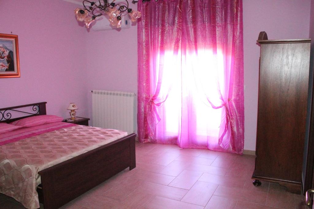 San Marzano di San GiuseppeにあるB&B Grande Salentoのベッドルーム1室(ベッド1台付)、ピンクのカーテン付きの窓が備わります。