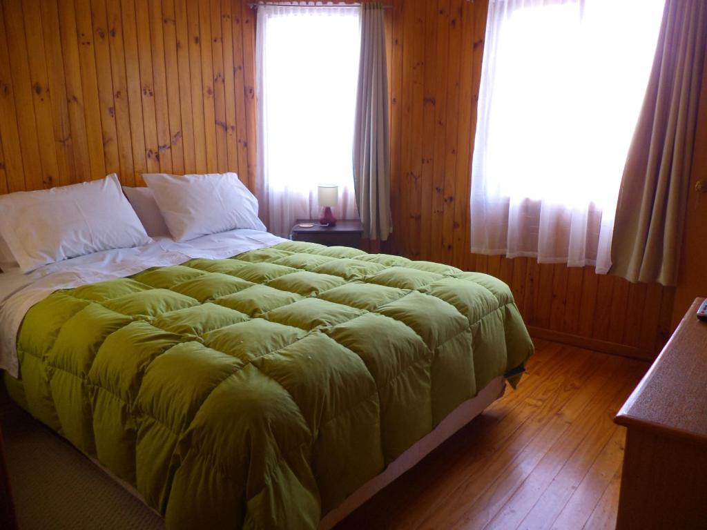 a bedroom with a large bed with a green blanket at Hospedaje Ayelen in Ancud