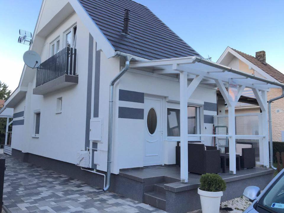 ein weißes Haus mit einer weißen Tür und einer Veranda in der Unterkunft Rita Apartmanház in Bük
