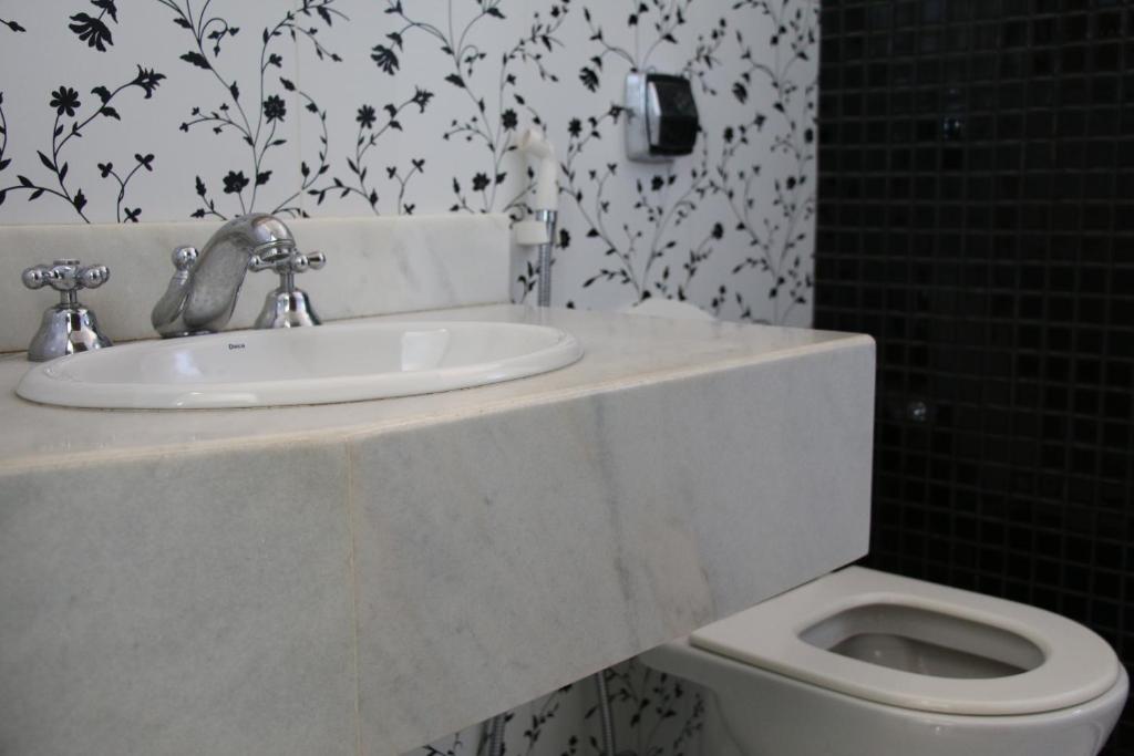 a bathroom with a sink and a toilet at Pousada Solar dos Guaras in Catas Altas