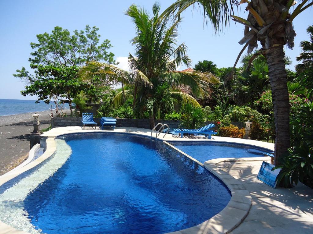 una piscina con 2 sillas y la playa en Three Brothers Bobby's Villas, en Amed