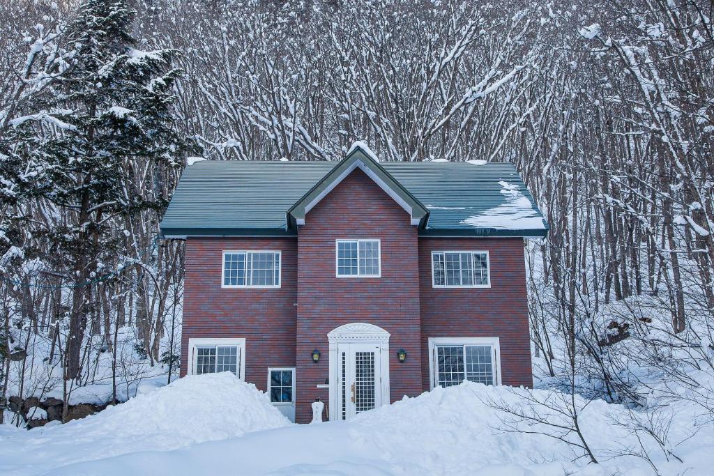 una casa rossa nella neve con gli alberi di The Bohemians' Shelter a Hakuba