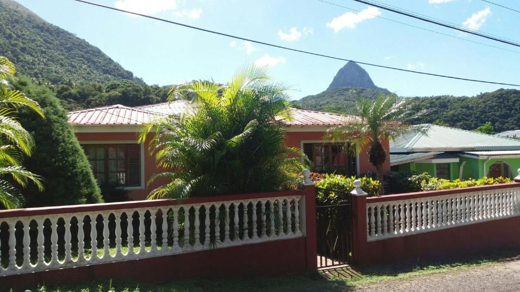 a house with a fence and a mountain in the background at cocoa pod studio in Soufrière