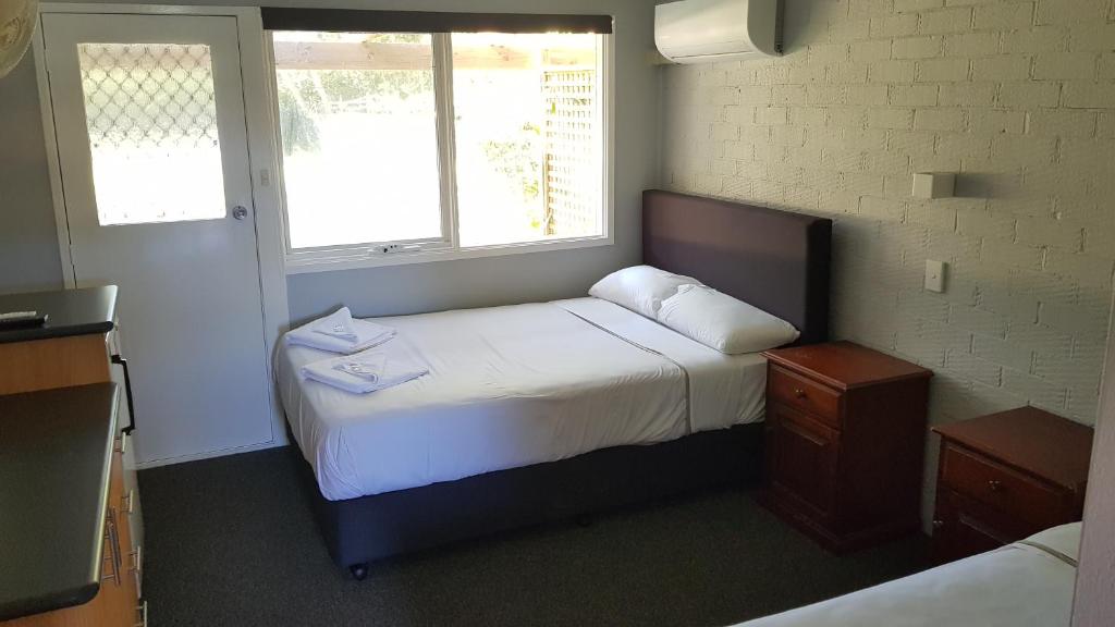 a bedroom with a bed and two windows at Bateau Bay Hotel in Bateau Bay