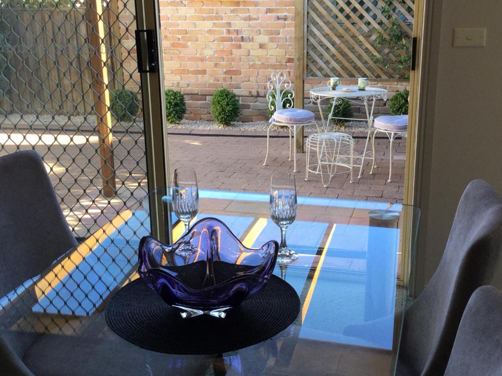 a glass table with two wine glasses on top of it at Tic Tac Toe Quality Accommodation in Armidale