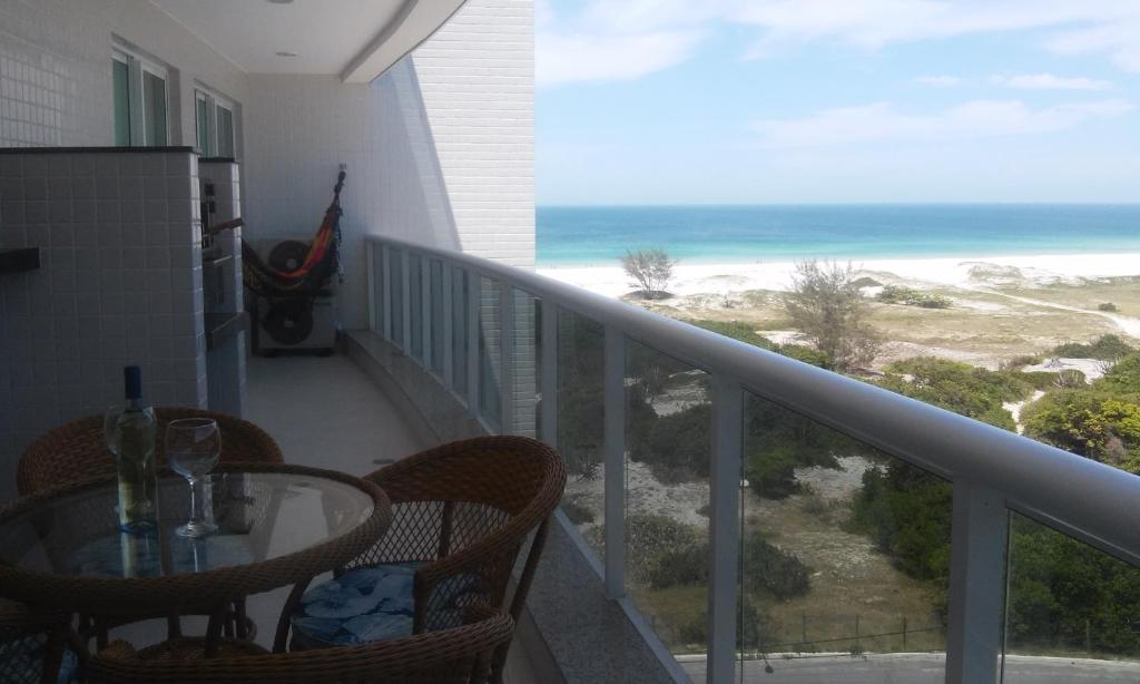 balcón con mesa, sillas y vistas al océano en Melhor condomínio de Arraial, en Arraial do Cabo