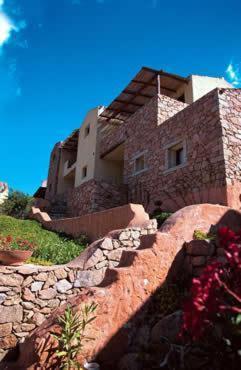 a building on top of a hill with some flowers at Residence I Cormorani Alti in Baja Sardinia