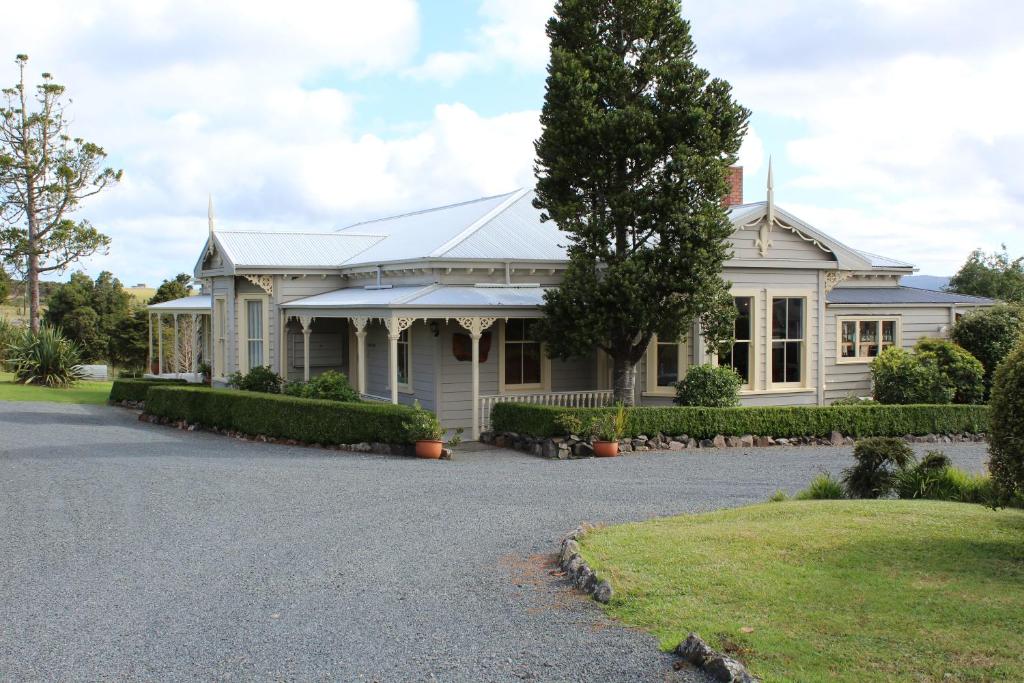 een wit huis met een oprit ervoor bij Waipoua Lodge in Donnellys Crossing