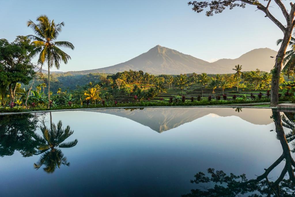 a pool of water with a mountain in the background at Ijen Resort and Villas - The Hidden Paradise in Banyuwangi