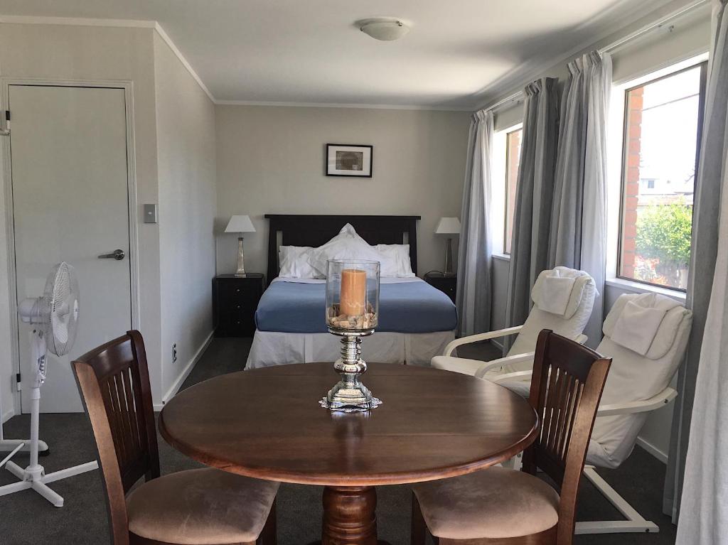 a bedroom with a bed and a table and chairs at Victoria Road B&B in Mount Maunganui