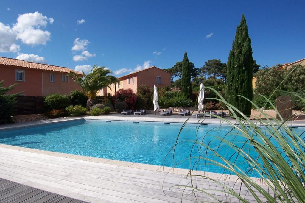 Una piscina en un patio con sillas y árboles. en CEDRAT, en Porto Vecchio