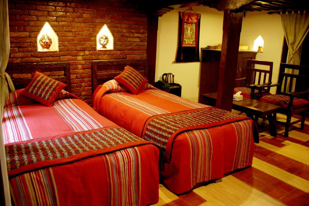 een slaapkamer met 2 bedden en een bakstenen muur bij Temple House in Kathmandu