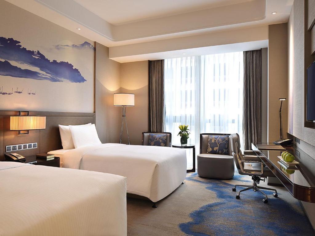 a hotel room with two beds and a desk at Wanda Realm Neijiang in Neijiang