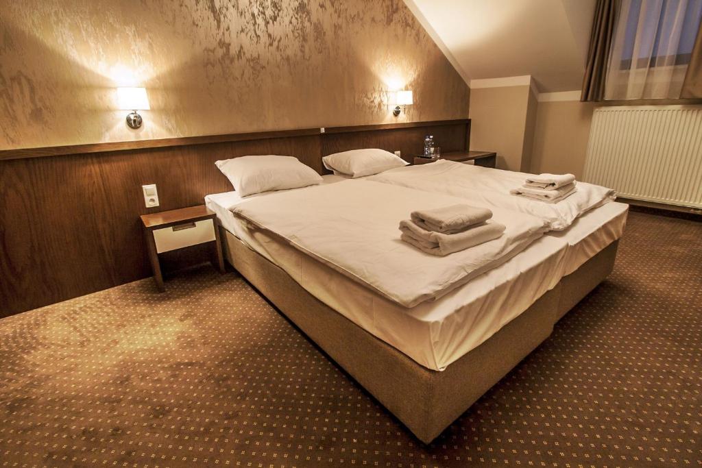 a bedroom with a large bed with towels on it at Hotel Tatarscy in Kalwaria Zebrzydowska