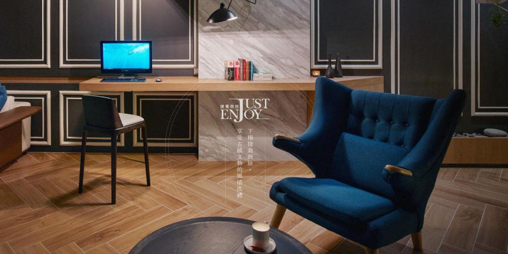 a living room with a blue chair and a television at Just Enjoy Business Hotel in Tainan