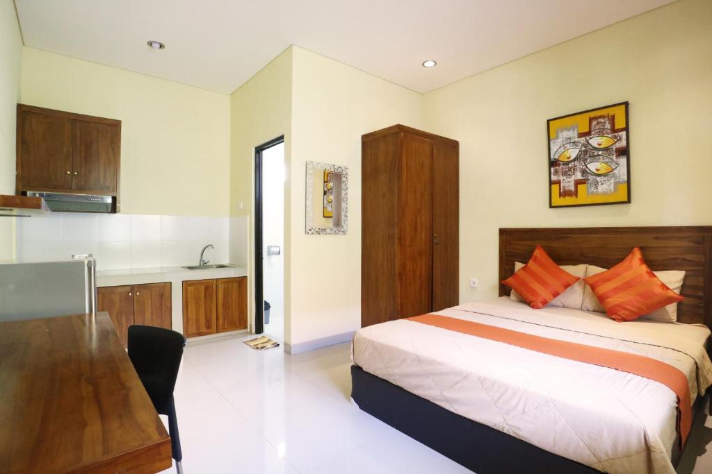 a bedroom with a bed and a kitchen at Dee Mansion in Denpasar