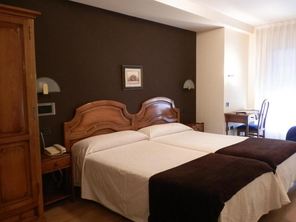 um quarto com uma cama grande e uma cabeceira em madeira em Hotel Doña Nieves em Noreña