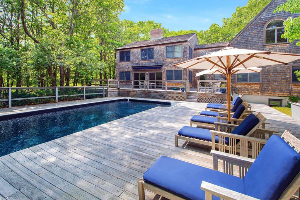 uma piscina com cadeiras e um guarda-sol em Villa Nostro Palazzo em East Hampton