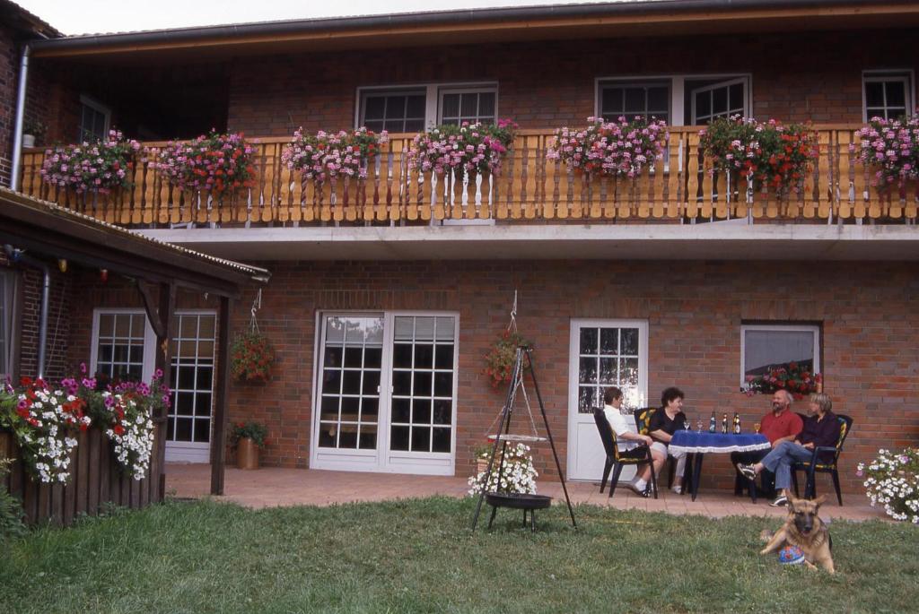 un grupo de personas sentadas alrededor de una mesa en un patio en Ferienhof Meyer Landhotel en Petershagen