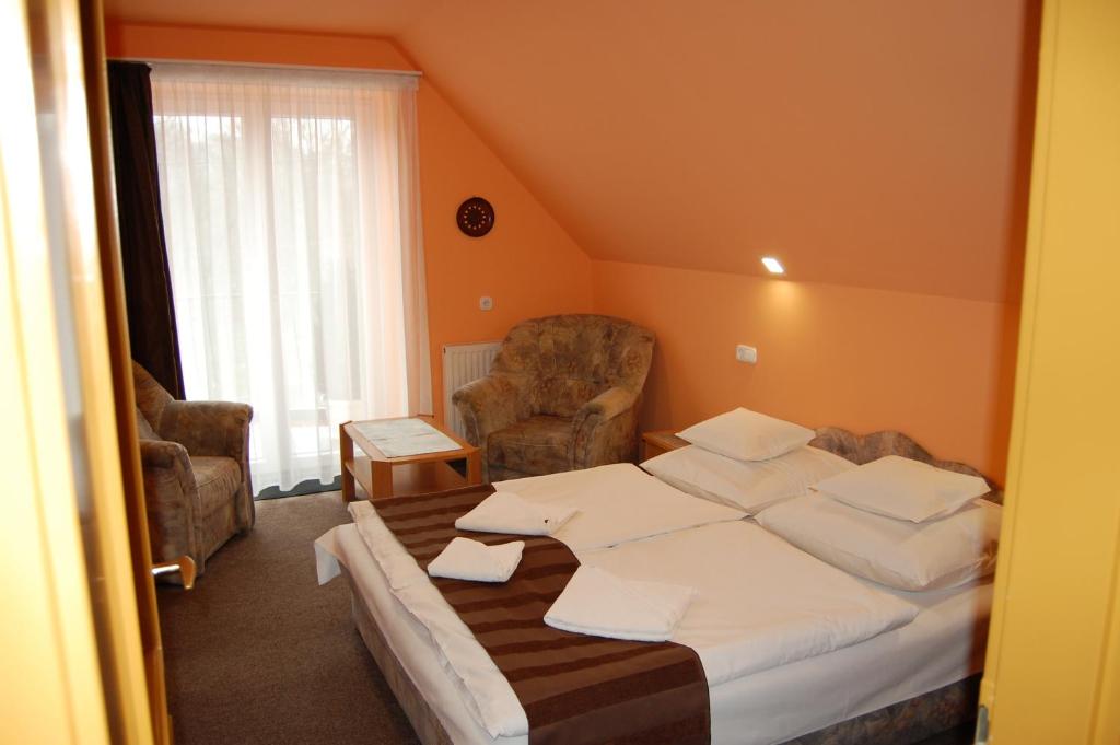 Habitación de hotel con 1 cama y 2 sillas en Judit Panzio, en Gyulakeszi