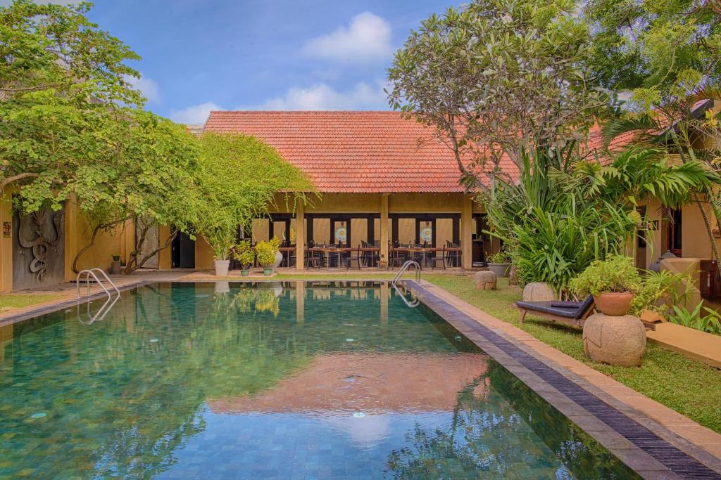 a swimming pool in front of a house at Jetwing Ayurveda Pavilions - Full Board & Treatments in Negombo