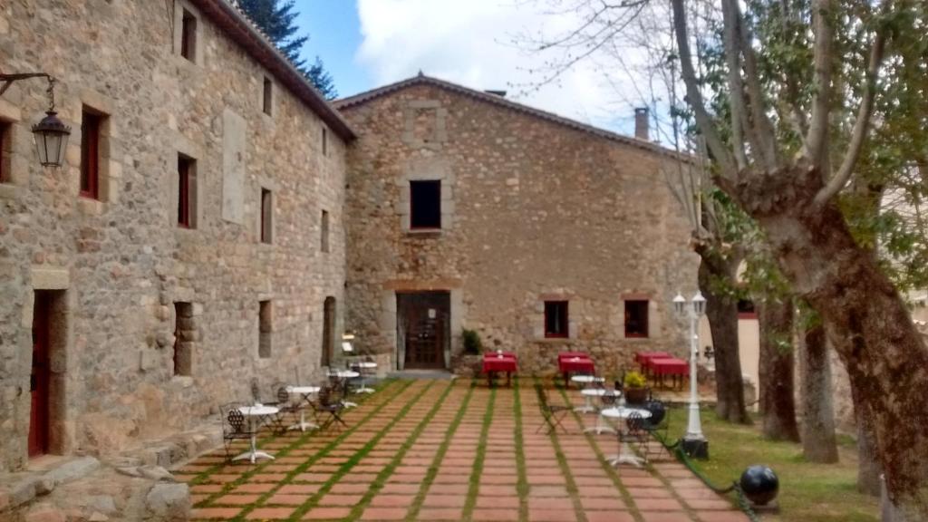 a stone building with tables and chairs in front of it at Sant Marçal del Montseny in Montseny