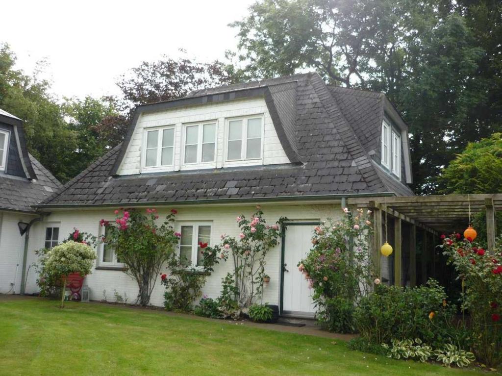 a white house with a black roof and a yard at Ferienwohnung Doelling in Ausacker