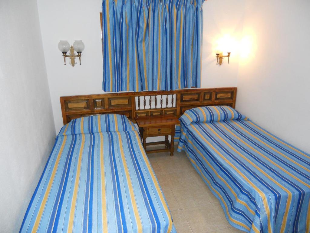 2 Betten in einem Zimmer mit blauen und gelben Streifen in der Unterkunft Apartamentos Los Juncos II in Playa del Ingles