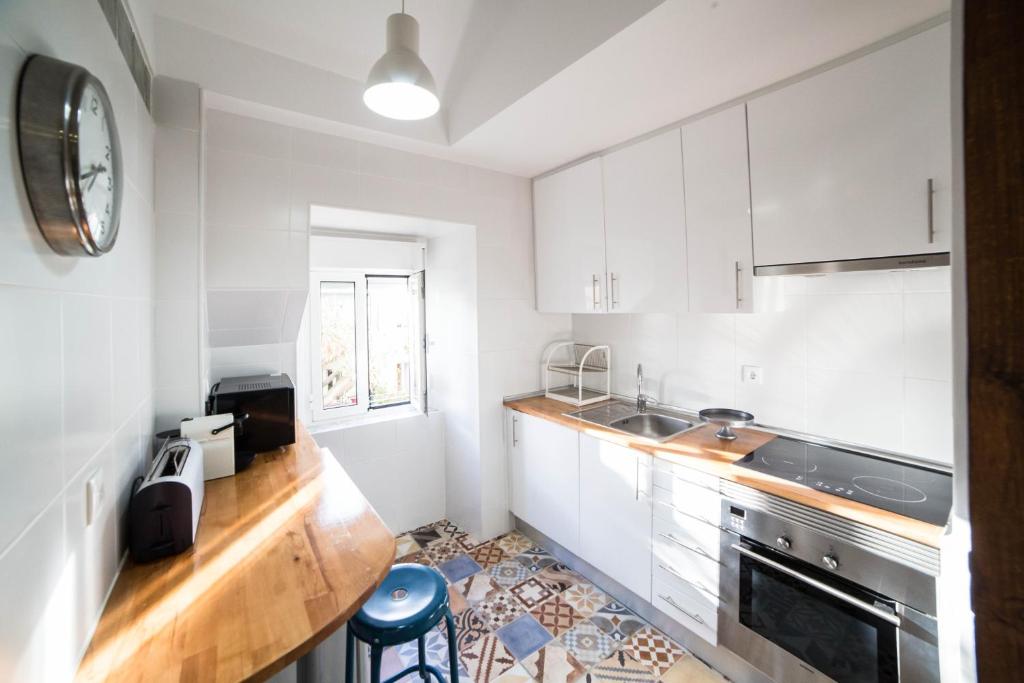 uma cozinha com armários brancos e um relógio na parede em FLH Fresh and Cozy Old Town Duplex em Lisboa