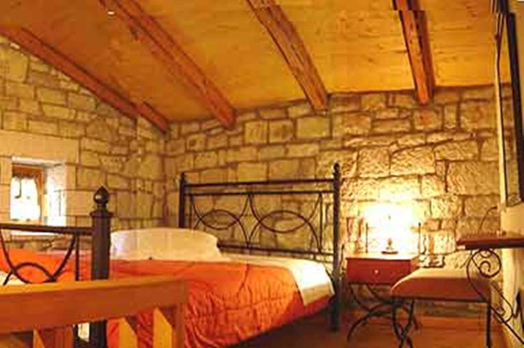 sypialnia z łóżkiem i kamienną ścianą w obiekcie Lithos w mieście Sirmbáni