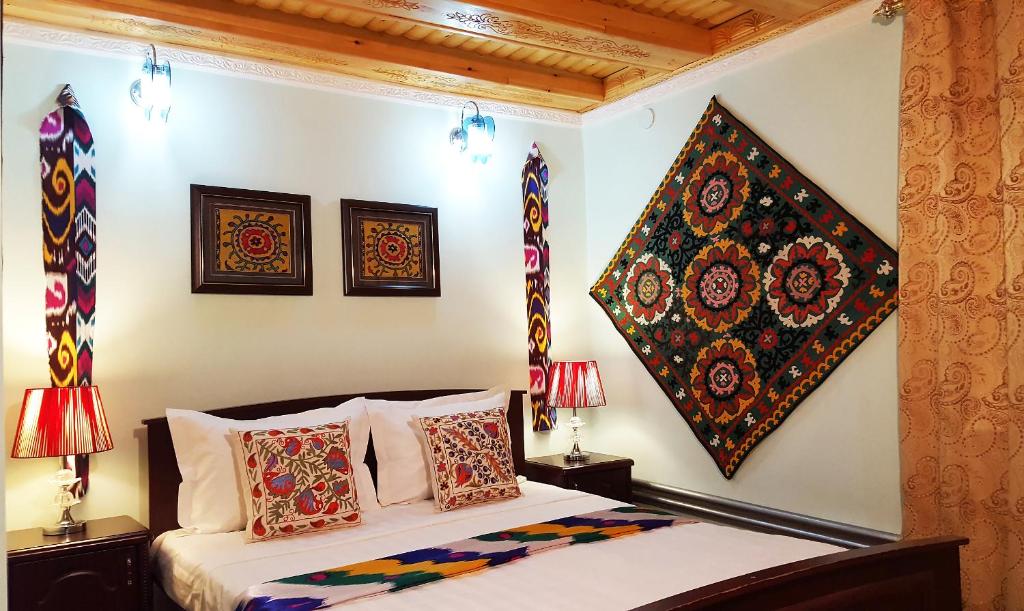 a bedroom with a bed with pillows and paintings on the wall at Jahongir in Samarkand