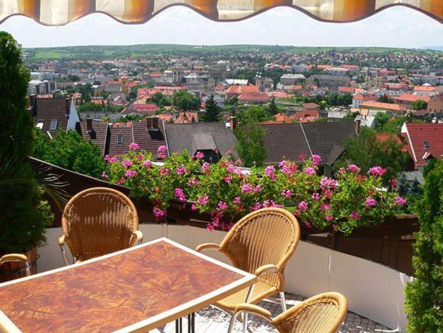 a table and chairs on a balcony with flowers at Ferienhaus Apartmanház Zalánki in Eger