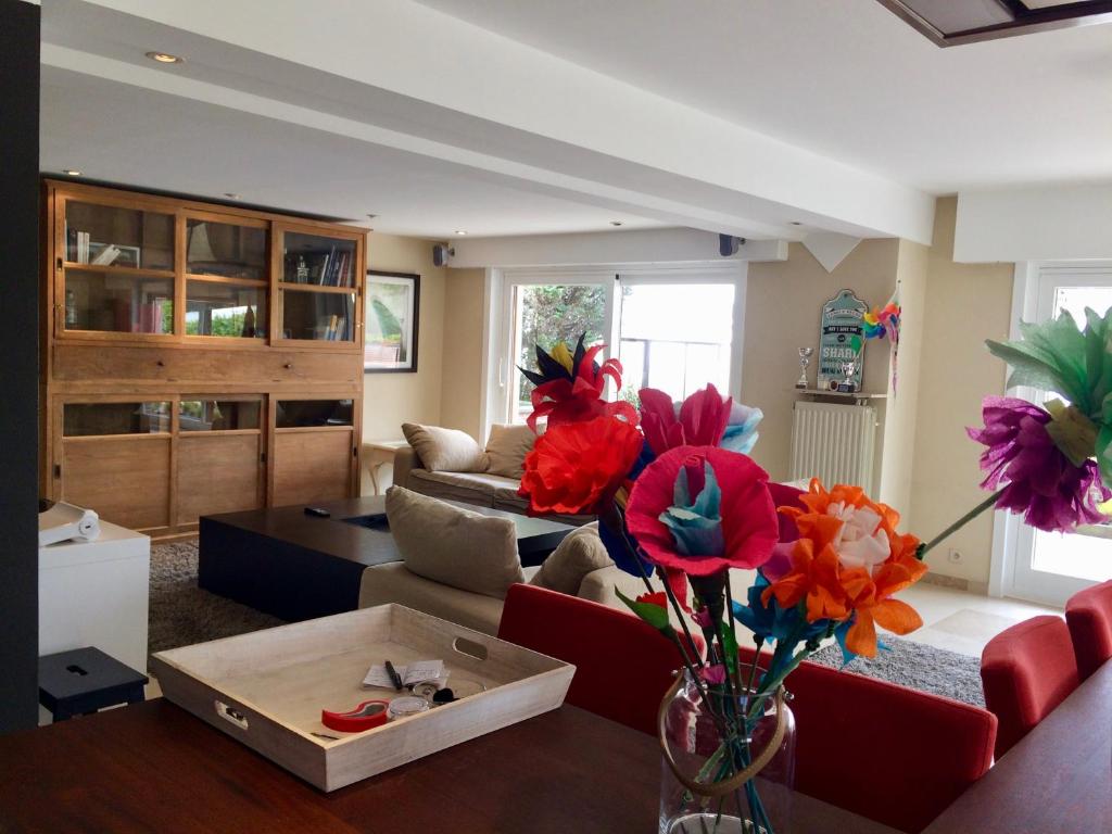 a living room with a red couch and flowers in a vase at Grand appartement avec terrasse in Knokke-Heist
