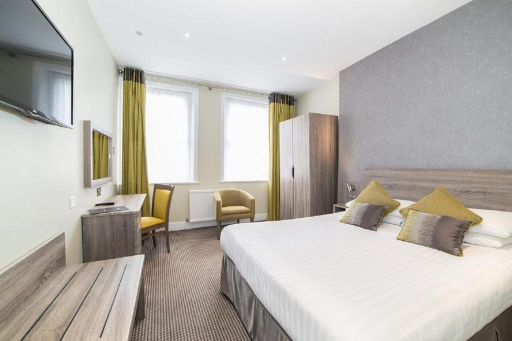 um quarto de hotel com uma cama grande e uma televisão em Phoenix Hotel em Londres