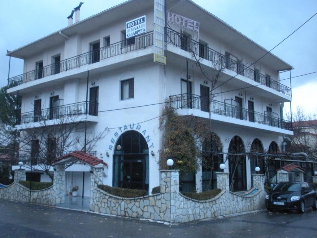 un edificio blanco con un coche aparcado delante de él en Villa Kalavrita Hotel, en Kalavrita