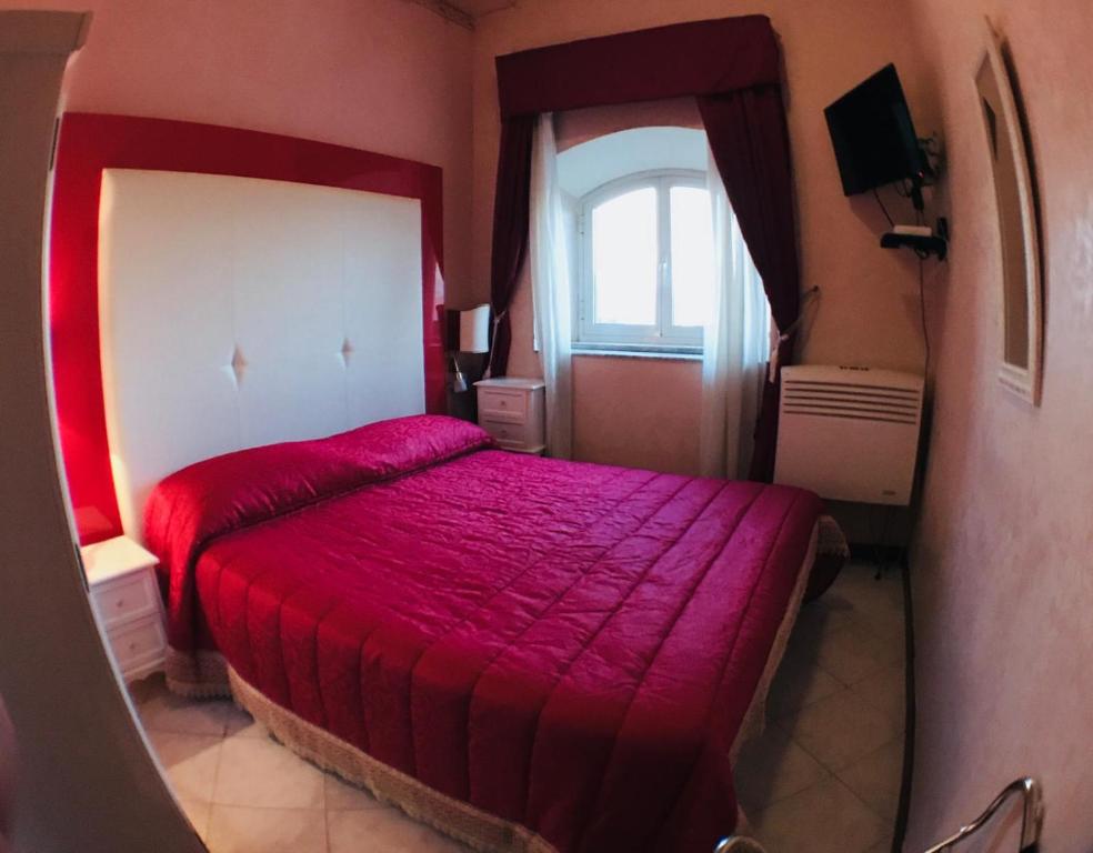 una camera con letto rosso e finestra di Albergo Panorama a Frascati