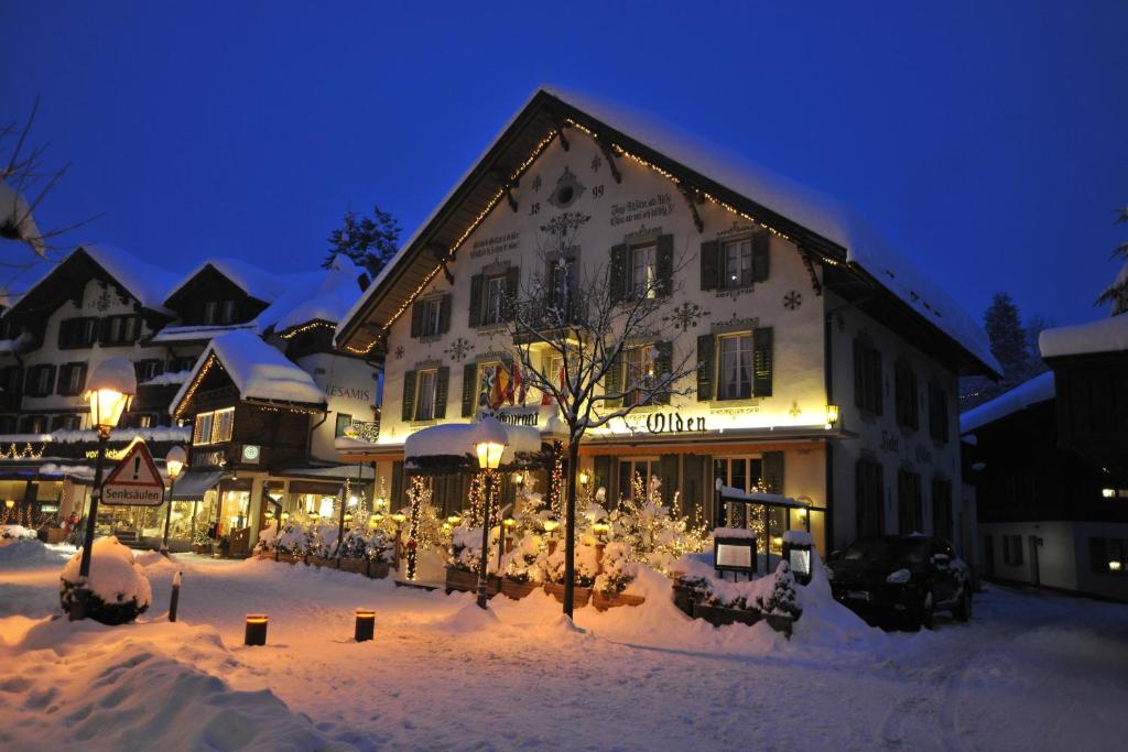 un gran edificio en la nieve por la noche en Hotel Olden, en Gstaad