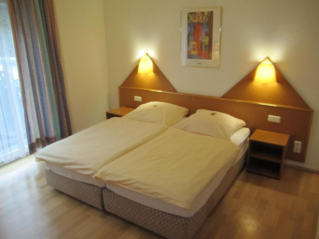 a bedroom with a large white bed with two lamps at Hotel Fährhaus in Saarbrücken