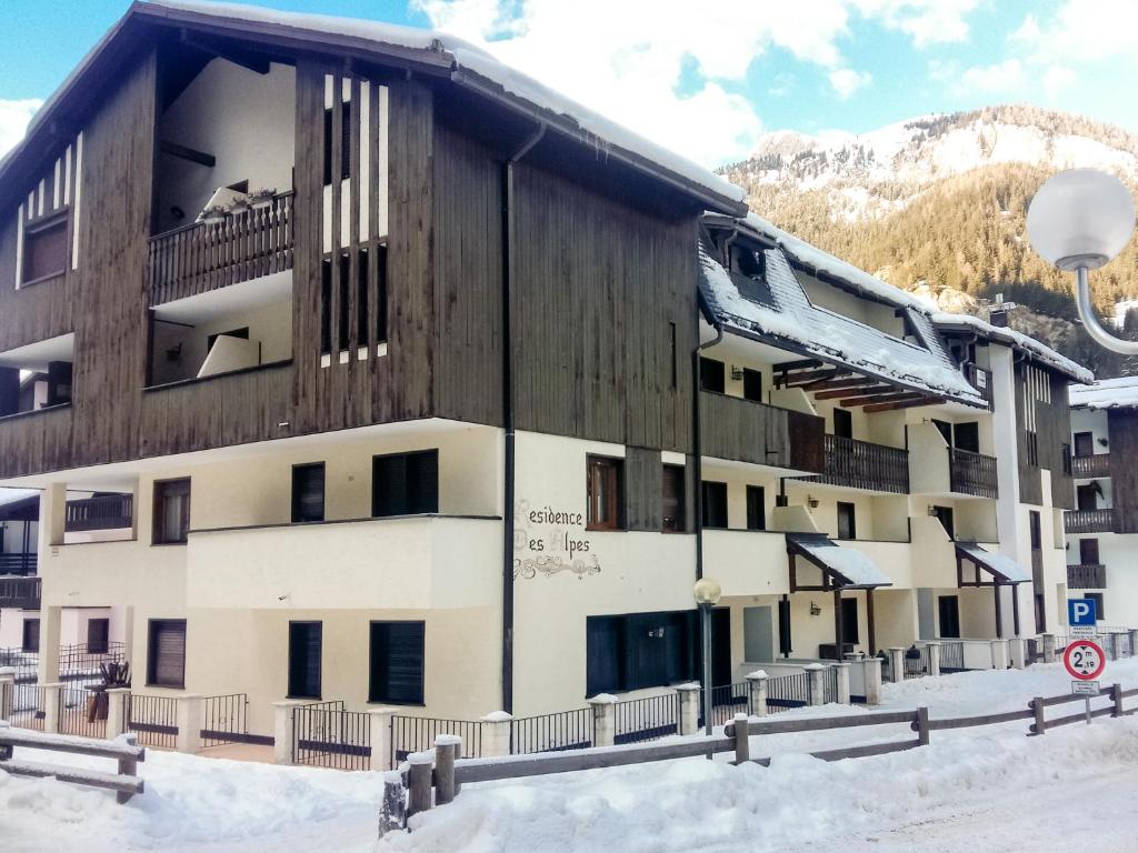 un edificio en la nieve frente a una montaña en Residence Des Alpes en Canazei