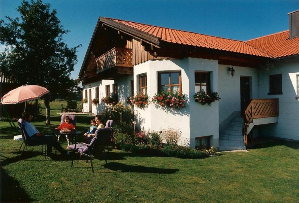 un gruppo di persone seduti sulle sedie di fronte a una casa di Ferienwohnung Familie Resch a Wegscheid