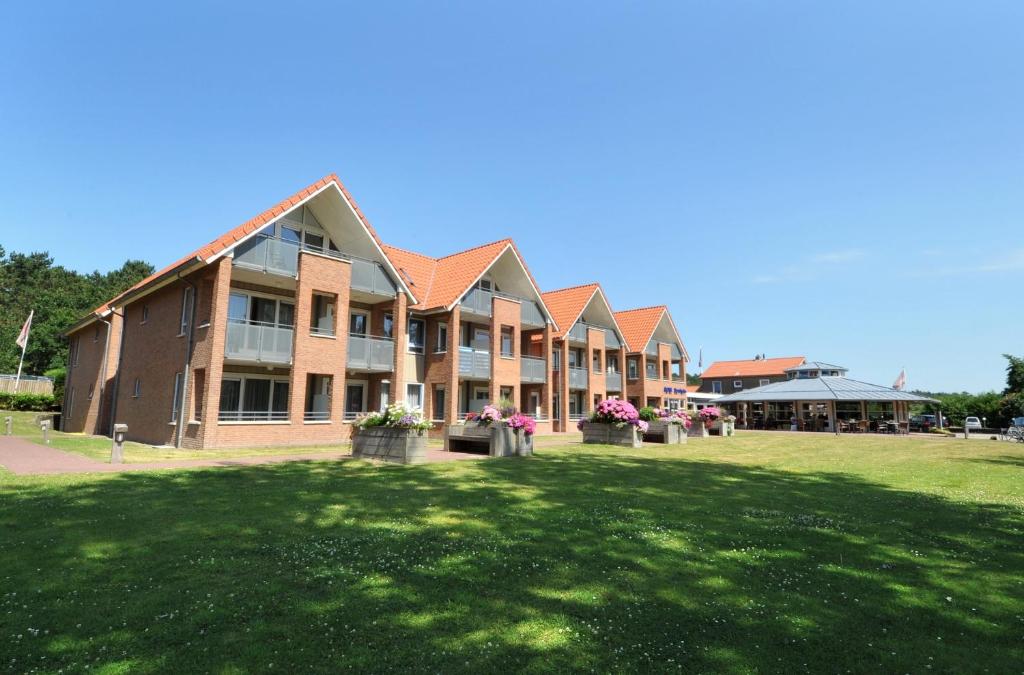 een groot bakstenen gebouw met een gazon ervoor bij Hotel Bornholm in West-Terschelling