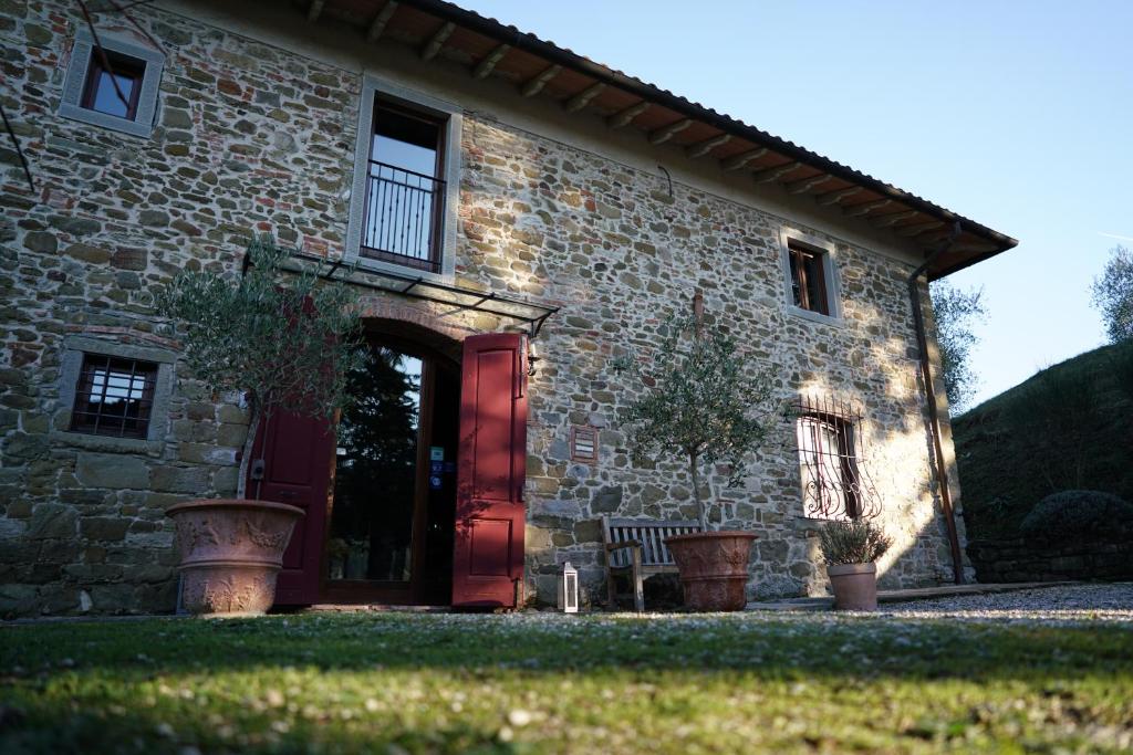 a brick house with a red door and a bench at SommaVilla B&B in Vicchio