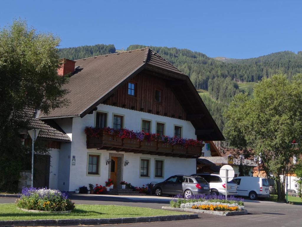 une grande maison blanche avec un toit en bois dans l'établissement Haus Edelweiss, à Sankt Margarethen im Lungau