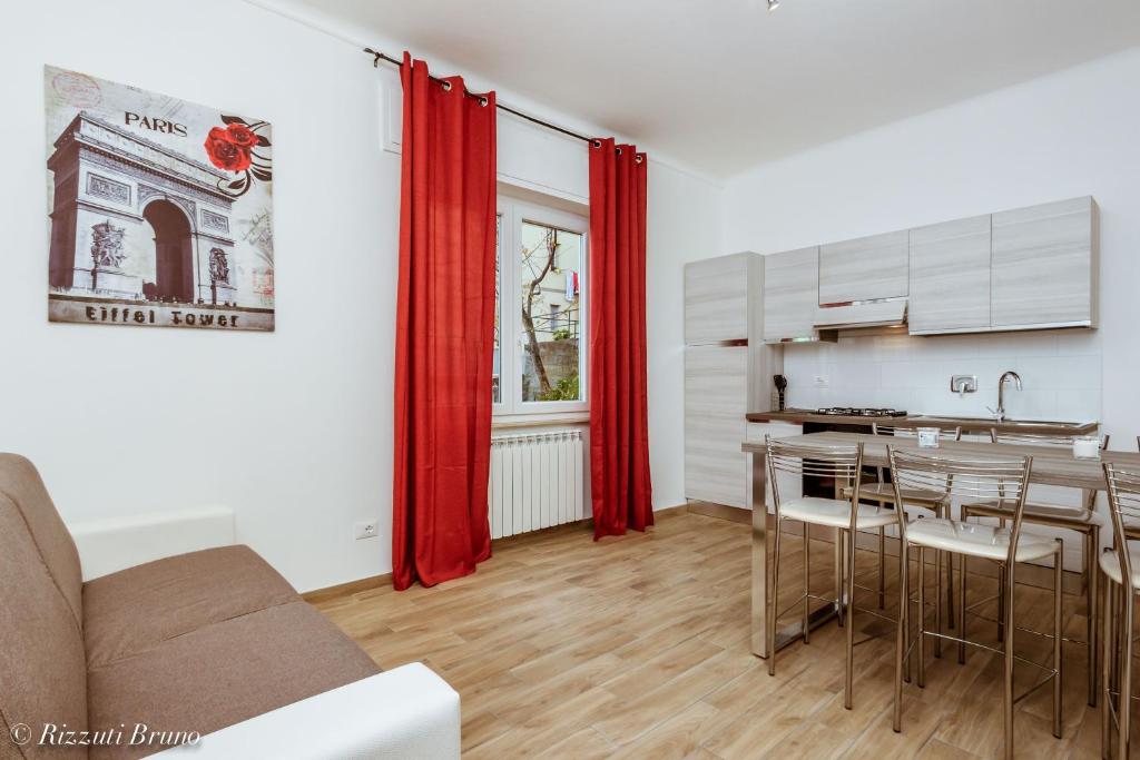 a living room with a table and a kitchen with red curtains at Happy House in Savona