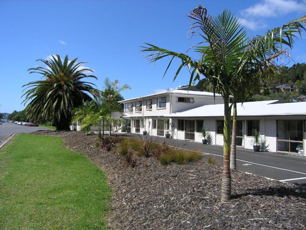 a palm tree in front of a building at Aarangi Tui Motel in Paihia