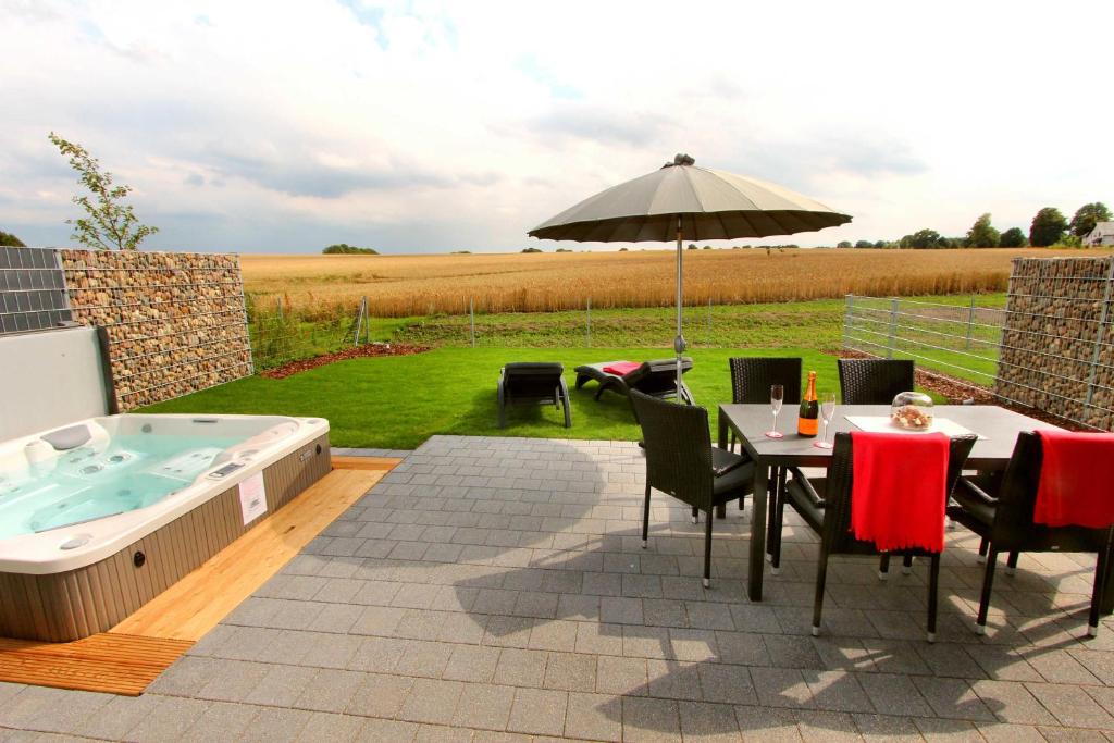 een patio met een tafel, een parasol en een hot tub bij Ferienhaus CASA OASIS in Göhren-Lebbin